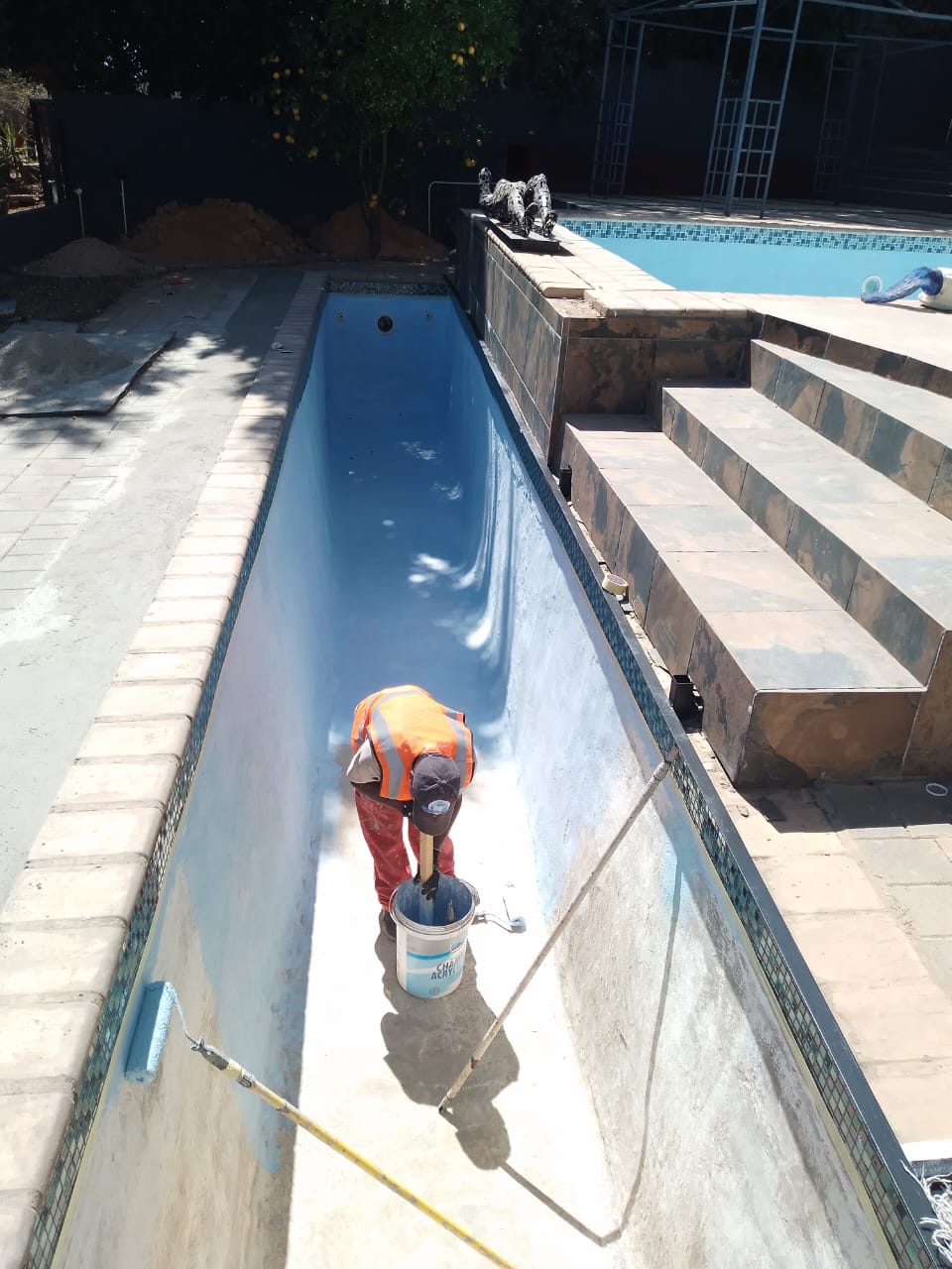 worker resurfacing swimming pool