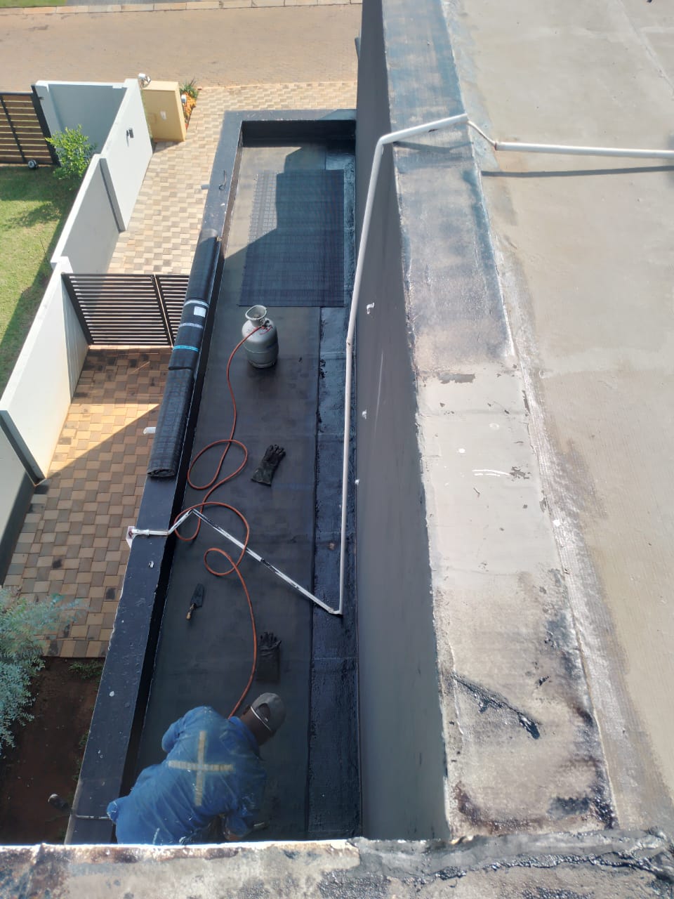 worker applying torch-on waterproof membrane on flat roof