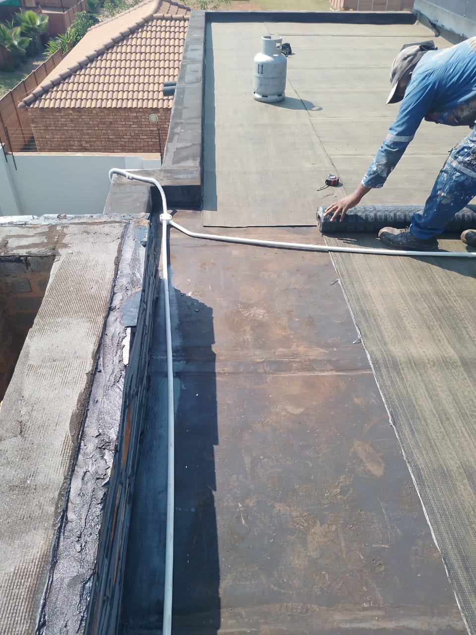 worker applying waterproof membrane on flat roof